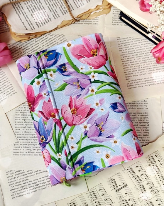 etui na książkę wzór piękna łąka na jasnym niebieskim  tle założone na książkę, przód